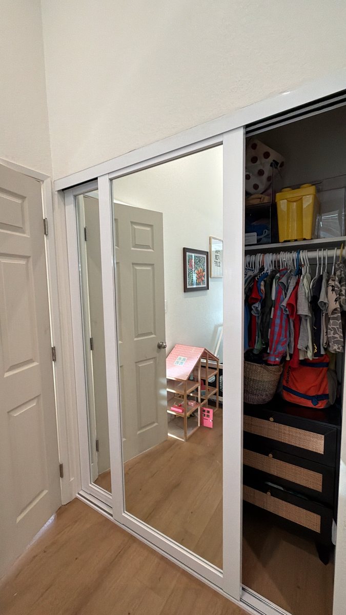 White frame mirror closet doors open, showing the closet