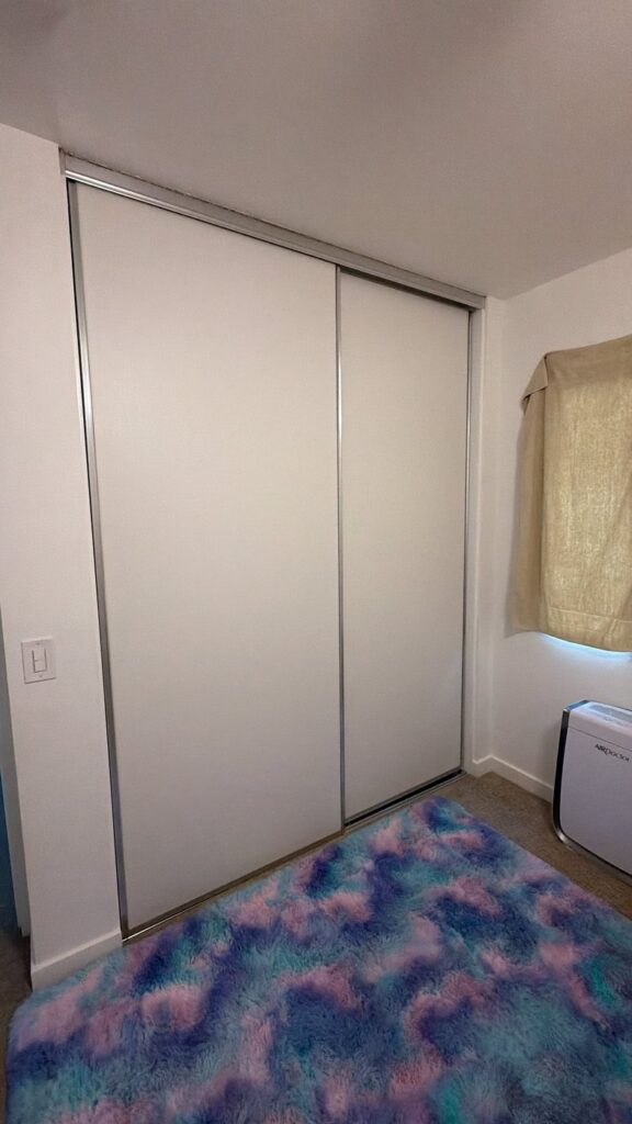 Plain white sliding closet doors in a standard Orange County bedroom