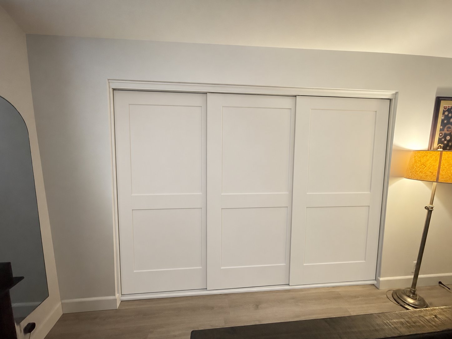 White Shaker-style wood doors installed on a three-panel triple-track sliding system